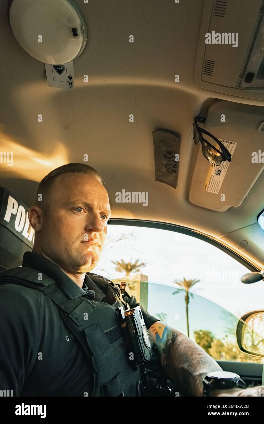Image verticale vue à angle bas de blanc homme de police caucasien assis à l'intérieur d'un véhicule cop comme saisie d'informations sur son voiture clavier comp Banque D'Images