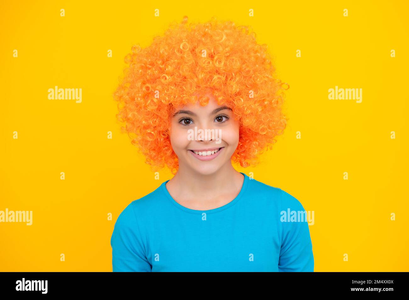 Fête d'anniversaire pour filles. Drôle d'enfant dans la perruque rouge curly. Temps de Amuse-toi bien. Jeune fille avec des cheveux orange, étant un clown. Joyeux portrait d'adolescent. Sourire Banque D'Images