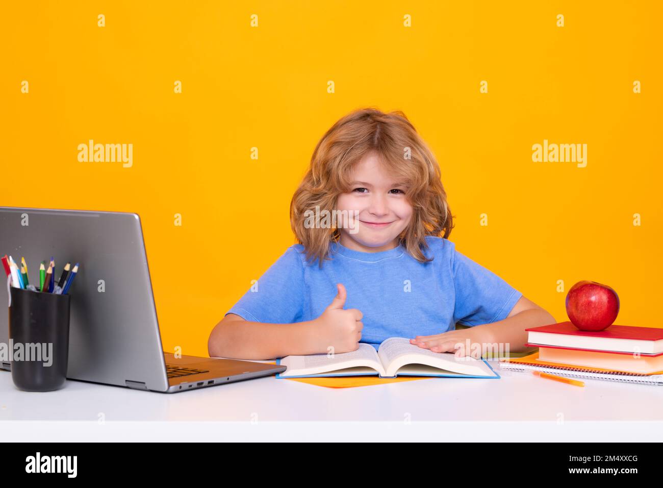 Enfant d'école étudiant en classe à l'école primaire. Enfant étudiant sur la leçon sur fond jaune isolé. Banque D'Images