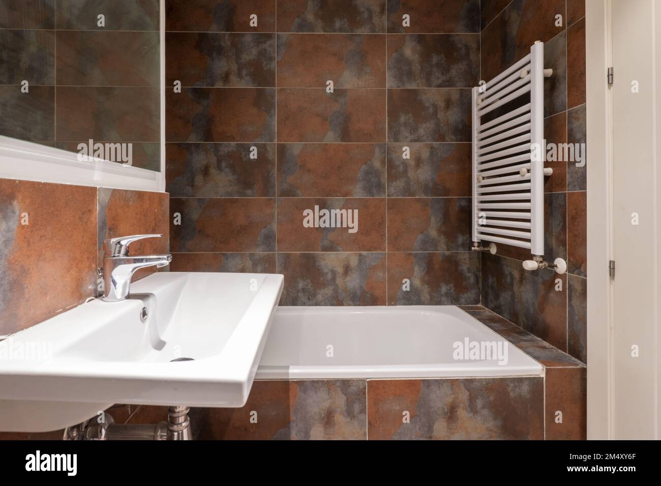 Salle de bains avec lavabo mural en porcelaine blanche sans armoire, miroir encadré de bois blanc, carreaux mouillés et porte-serviette blanc Banque D'Images