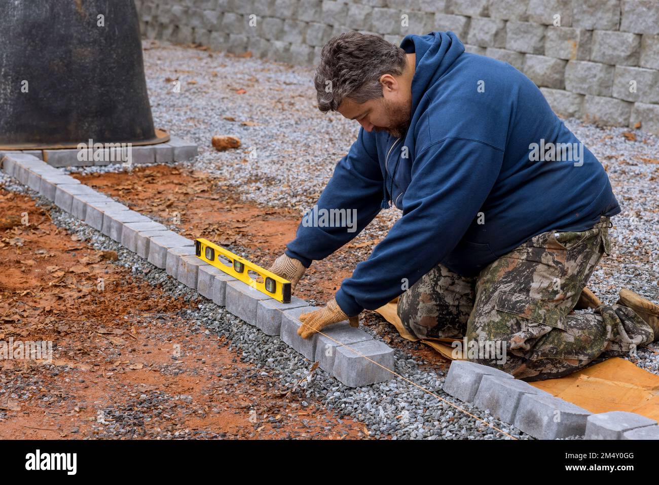 Ouvrier de construction posant des pavés en béton de pierre dans le cadre d'un projet de trottoir Banque D'Images