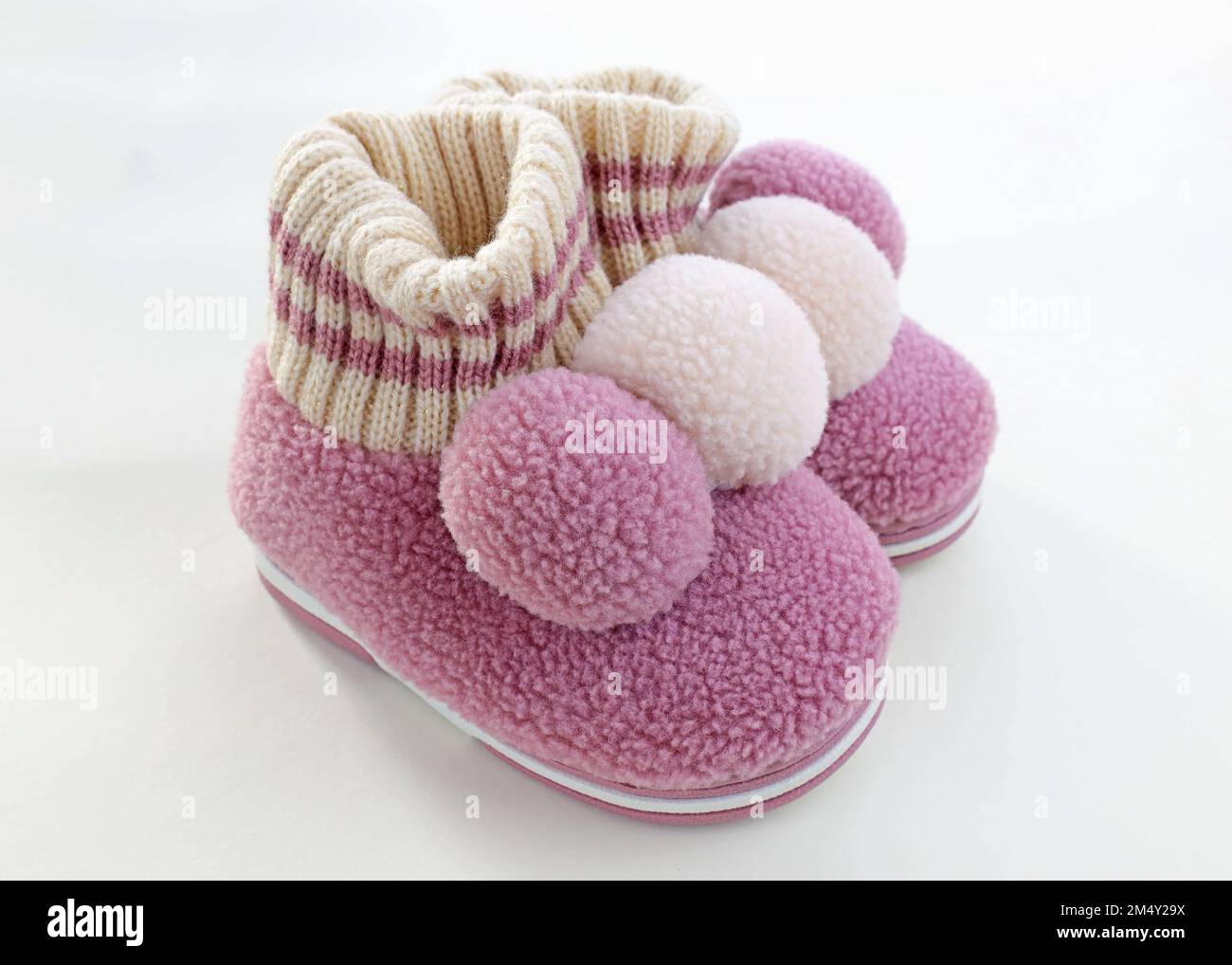 Chaussons en laine pour enfants avec balabon. Pantoufles chaudes roses pour filles. Une paire de chaussures pour enfant pour le froid sur fond blanc. Banque D'Images