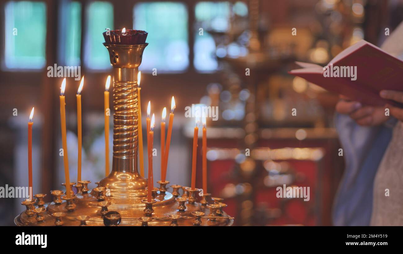 Des bougies allumées sur le fond du prêtre lisant la Bible au service. Banque D'Images