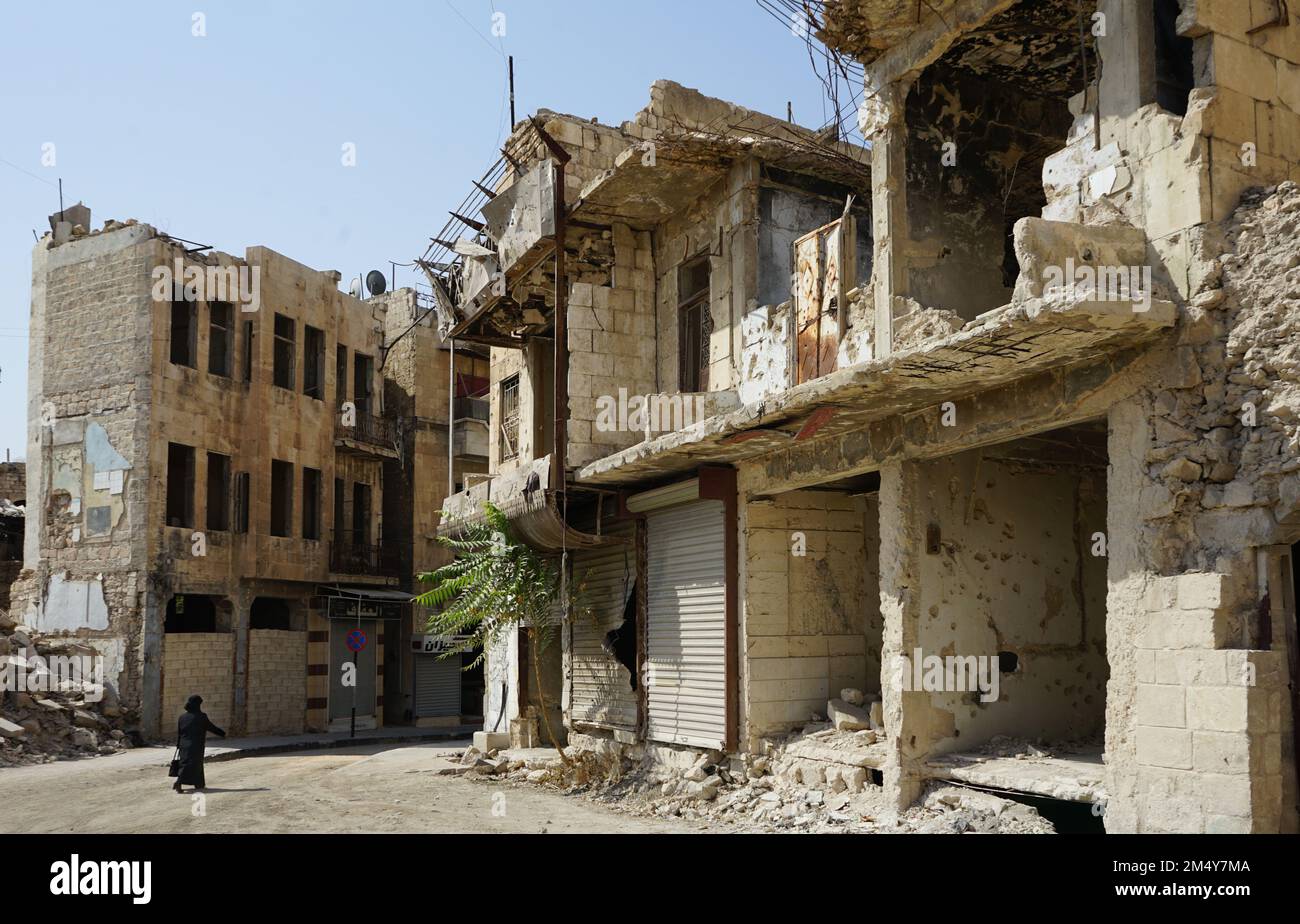 Une femme marche dans un quartier gravement endommagé d'Alep. La ville a subi des dégâts considérables dans des batailles féroces pendant la guerre civile syrienne. Syrie Banque D'Images