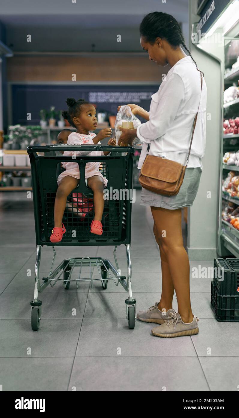 Pour moi. Photo en longueur d'une jeune mère qui fait du shopping à l'épicerie avec ses enfants. Banque D'Images