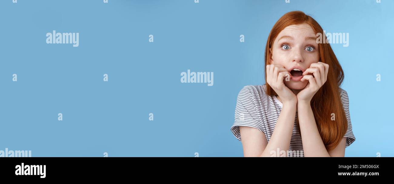 Une jeune fille à tête rouge à la tête rouge, choquée et sans voix, a été impressionnée par son observation stupéfaite moment important série tv mordant les doigts la bouche ouverte secouait debout Banque D'Images