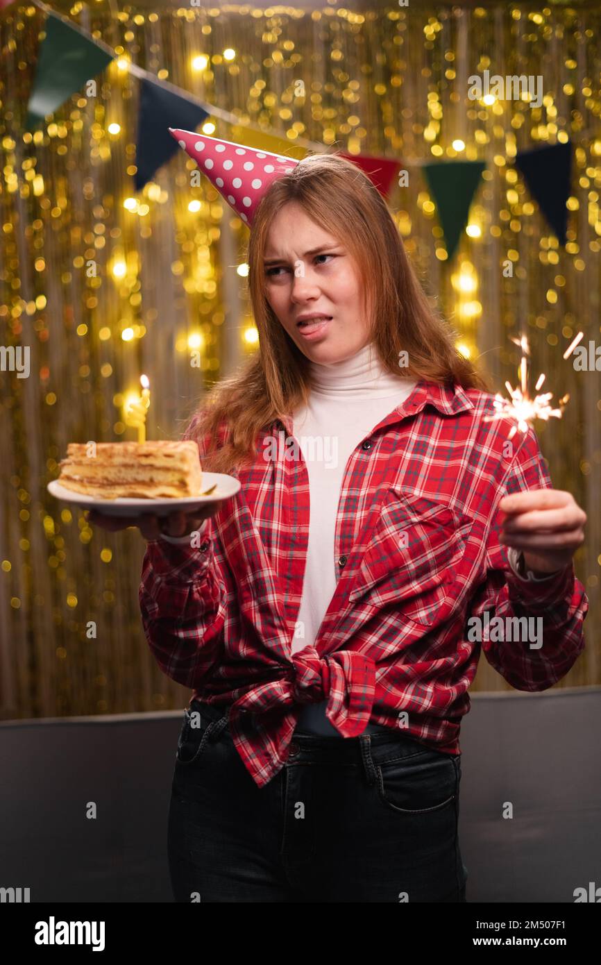 Photo d'un jeune homme malheureux triste mécontent mécontent, montrer la langue, avec gâteau d'anniversaire en fête dans le salon décoré à la maison. Copier l'espace Banque D'Images