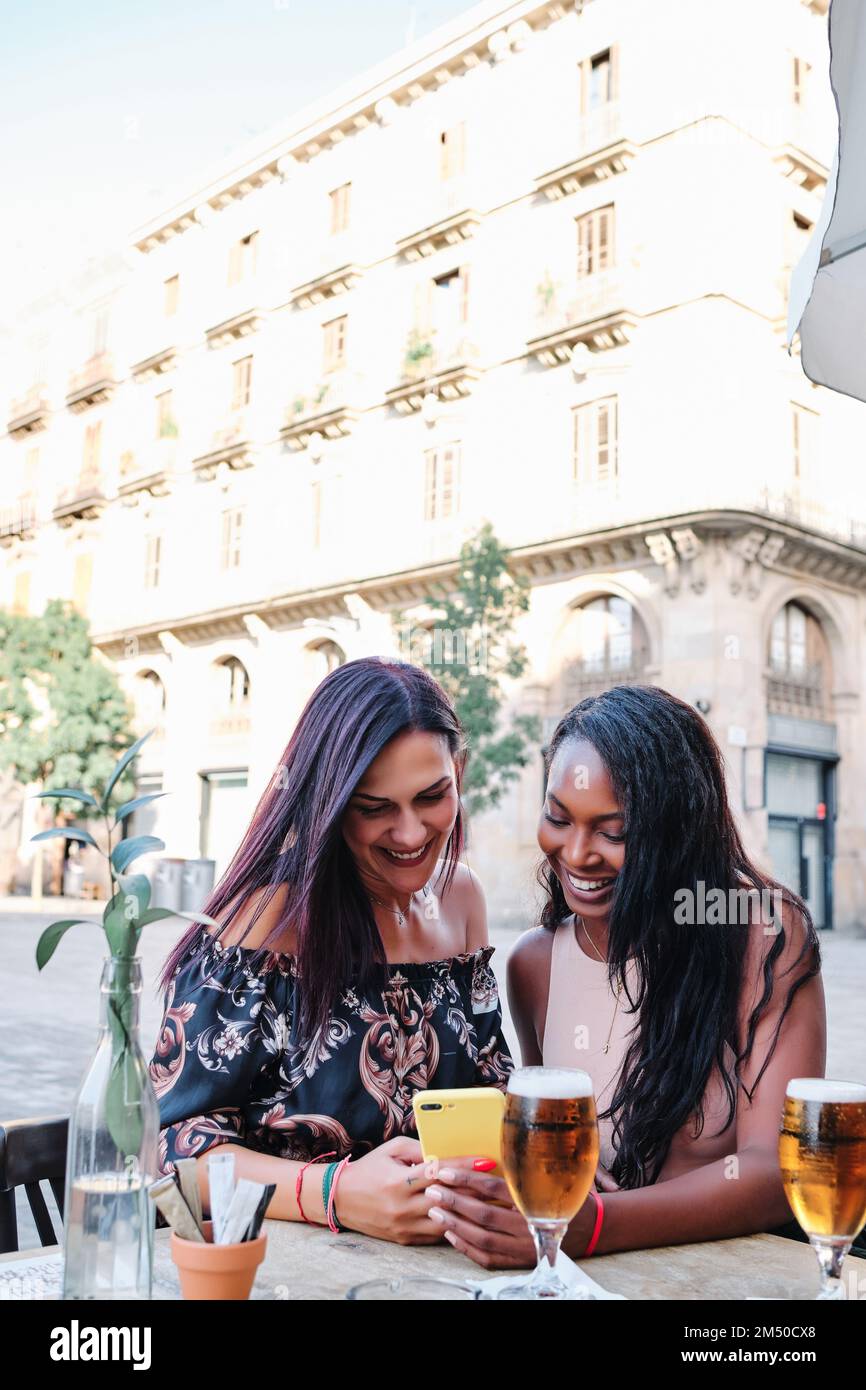 Amis multiethniques utilisant le mobile dans une terrasse de bar Banque D'Images