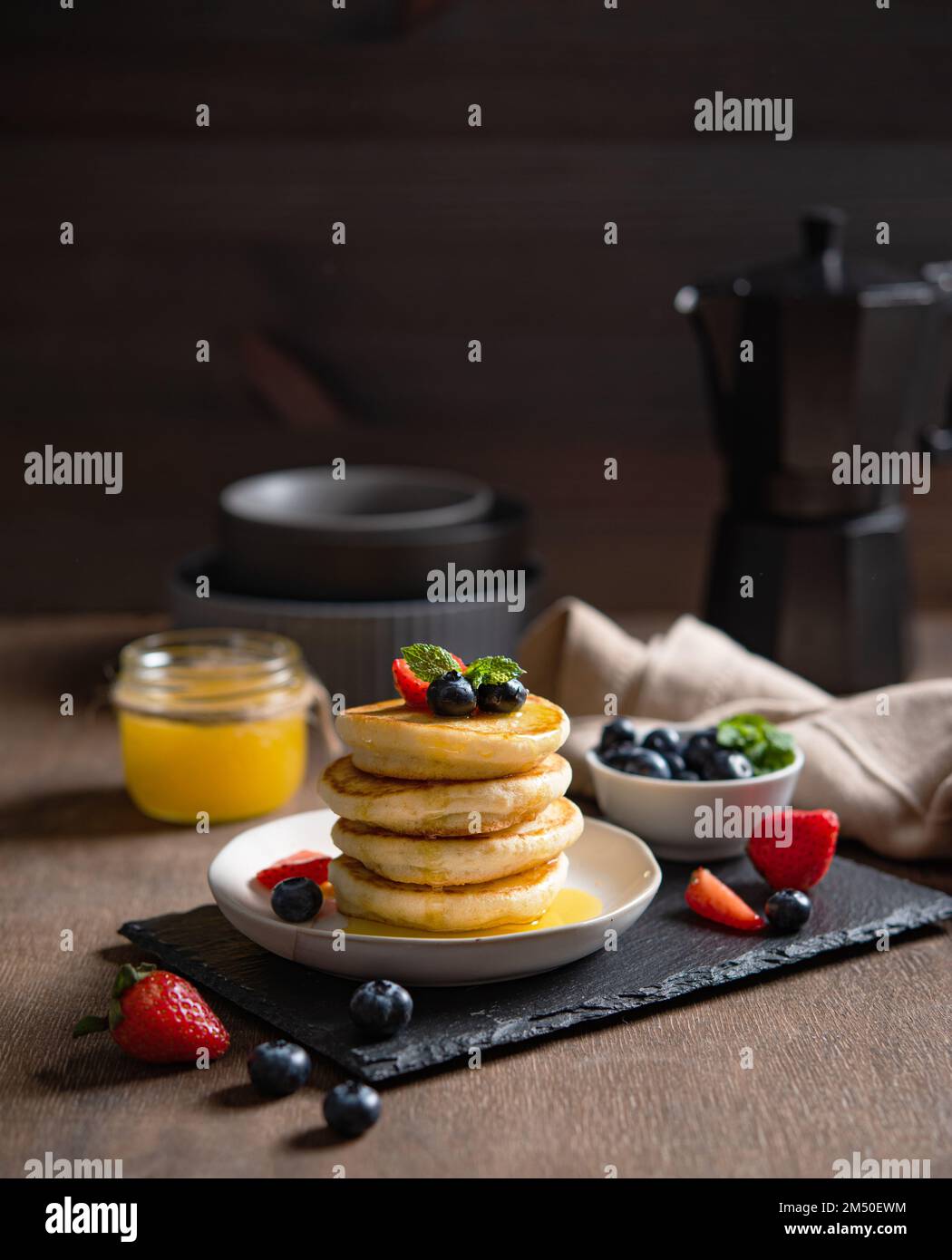 Délicieuses crêpes maison avec baies et miel sur fond de bois sombre et cafetière. Le concept d'un petit déjeuner sain et nutritif. RUS Banque D'Images