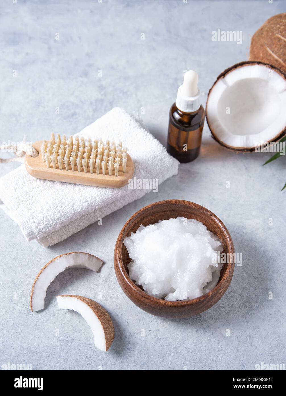 concept de spa biologique. Huile de noix de coco saine avec une brosse en bois et une moitié de noix de coco sur fond bleu. Macro et gros plan Banque D'Images