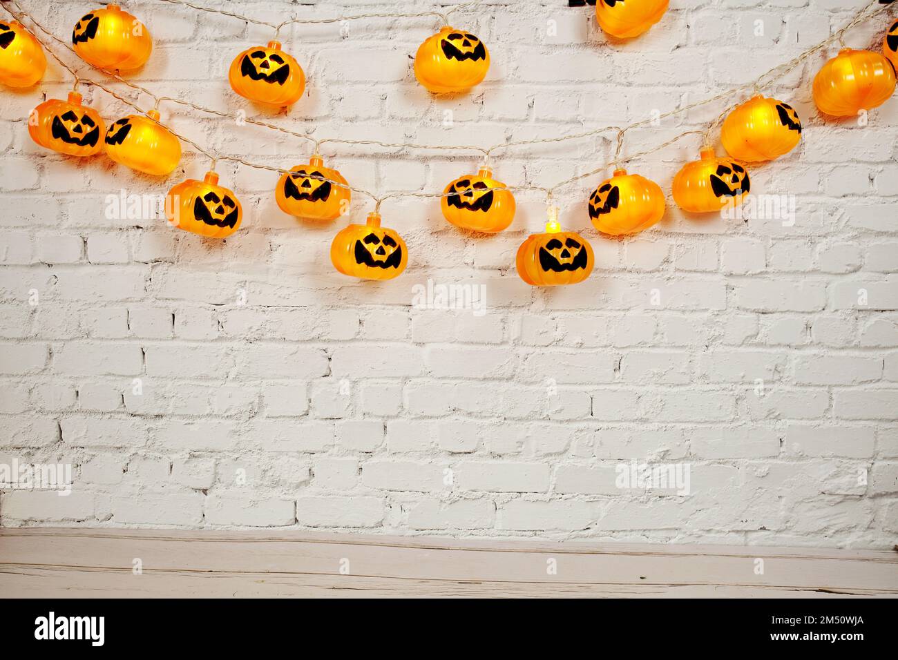 Lumières à DEL de citrouille pour Halloween décorations sur fond de mur de briques blanches Banque D'Images