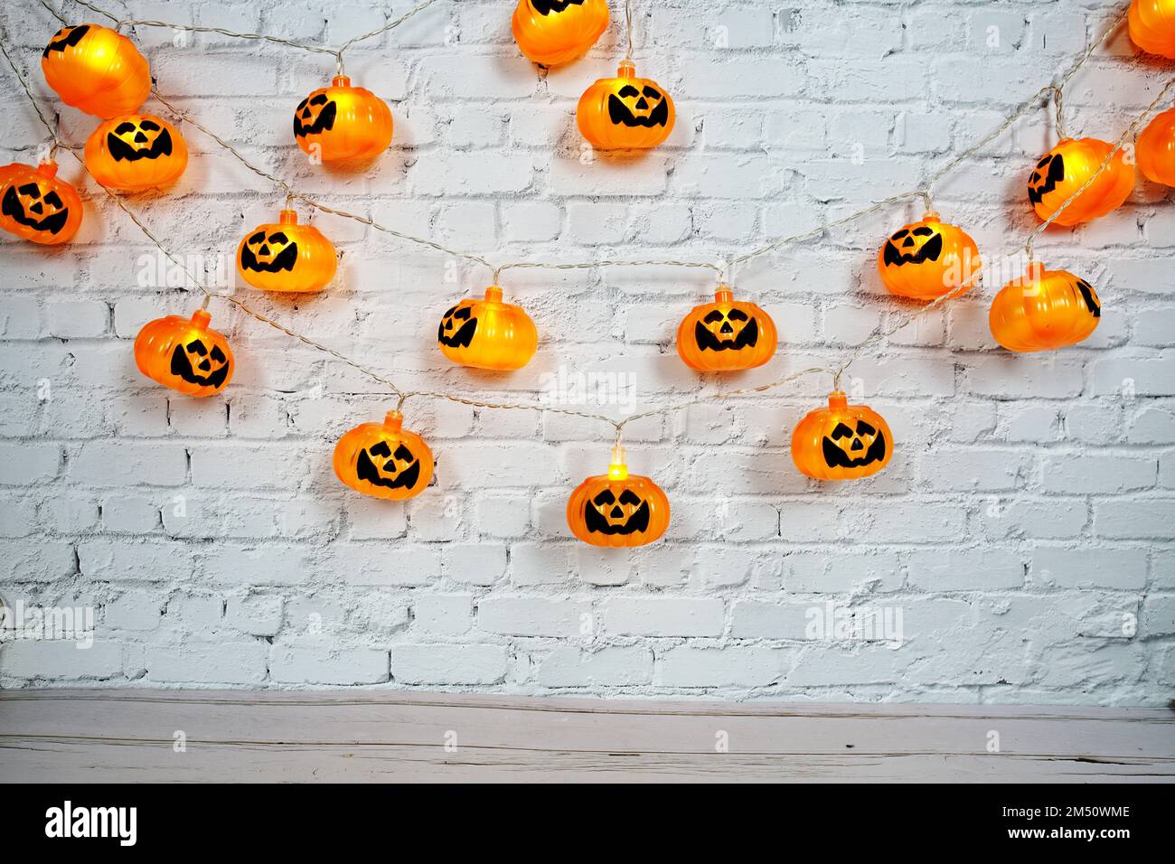 Lumières à DEL de citrouille pour Halloween décorations sur fond de mur de briques blanches Banque D'Images