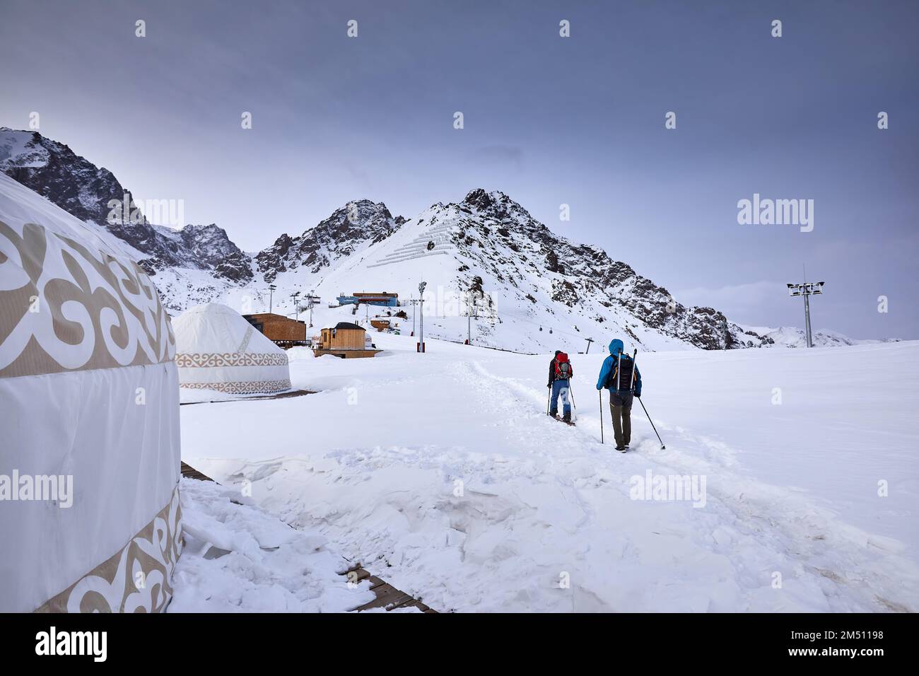Deux hommes skieurs ski avec sac à dos dans la haute montagne enneigée près de la maison de yourte traditionnelle nomade à la station de ski de Shymbulak à Almaty, Kazakhstan. Sport Banque D'Images