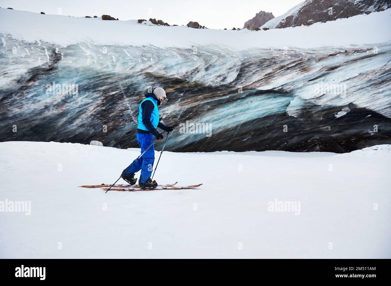 Skieur homme ski de randonnée à la station de ski de montagne haute neige de Shymbulak près de la paroi de la grotte de glace. Sport en plein air dans l'arrière-pays en hiver. Banque D'Images