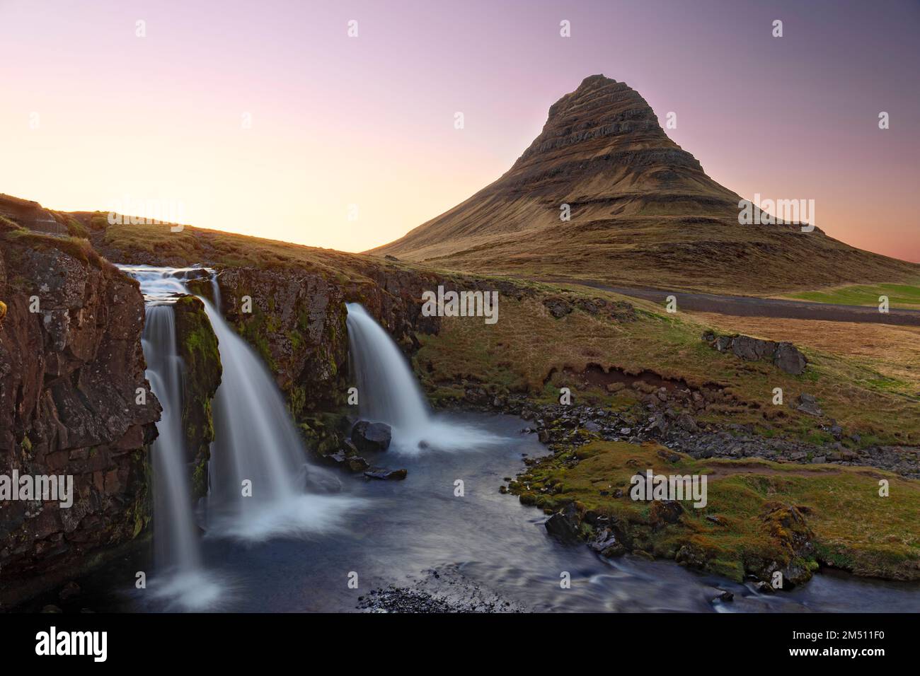 Montagne Kirkjufell, montagne contre ciel clair et chute d'eau en premier plan, région occidentale, Islande Banque D'Images