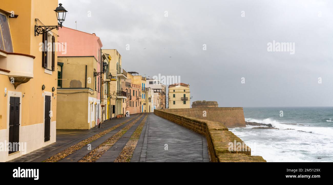 Alghero, Italie - 14 décembre 2022 : vue sur le front de mer historique avec murs fortifiés et défenses à Alghero sous un ciel couvert de tempête Banque D'Images