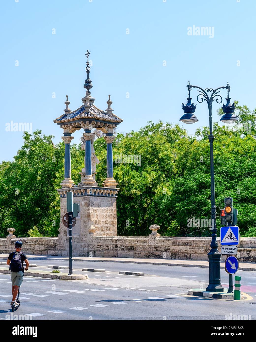 Un jeune homme conduit un scooter sur le pont Royal ou Puente del Real. La structure est un pont historique qui traverse l'ancienne rivière Turia. Banque D'Images