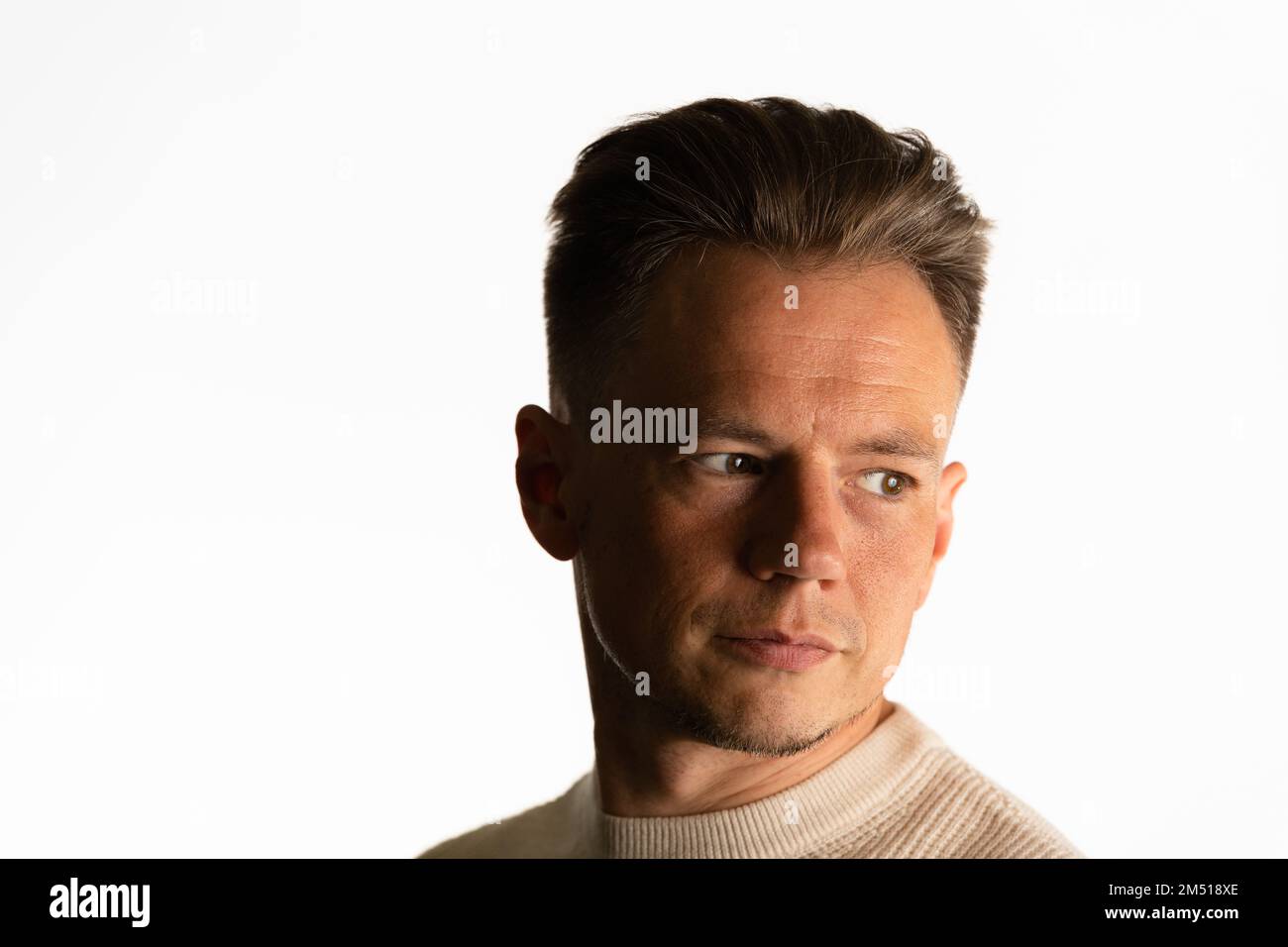 Photo de jeune beau attrayant sérieux portant un chandail de crème isolé sur fond blanc Banque D'Images