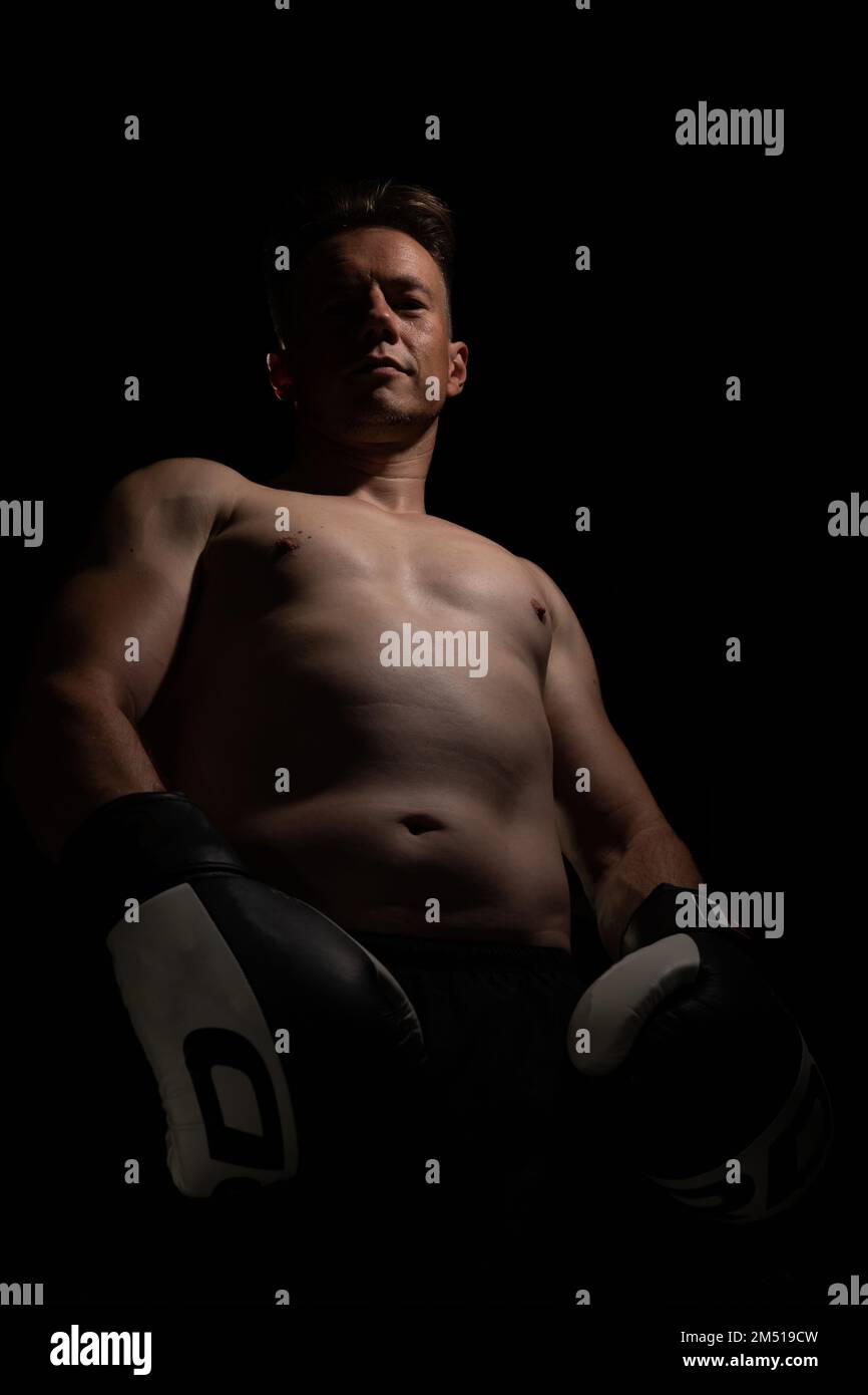 Portrait d'un homme musclé et sans pied portant des gants de boxe, isolé sur un fond noir Banque D'Images