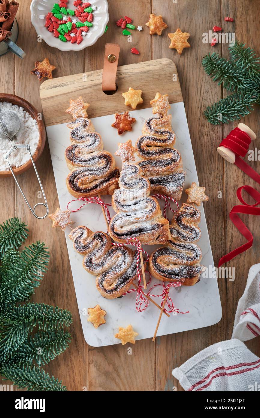 Gâteau feuilleté en forme d'arbre de Noël avec garniture au chocolat, poudre de sucre et sucettes sur fond de bois. Noël, hors-d'œuvre du nouvel an. Festif Banque D'Images