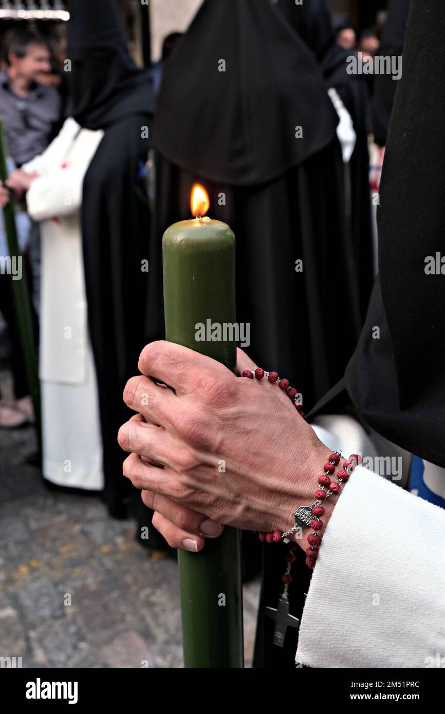 Confrères accompagnant les pasos dans l'itinéraire des 'Stations of Penance'. Vue rapprochée des mains avec la bougie Banque D'Images