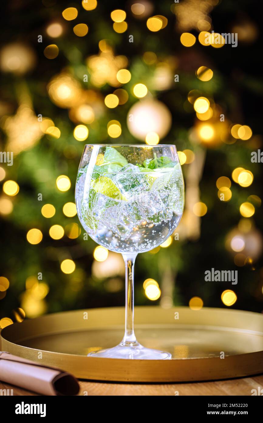 Verre transparent au verre avec glace, et citron vert sur un tableau rustique sombre dans la décoration de Noël avec arbre de Noël et lumières dans le dos flou Banque D'Images