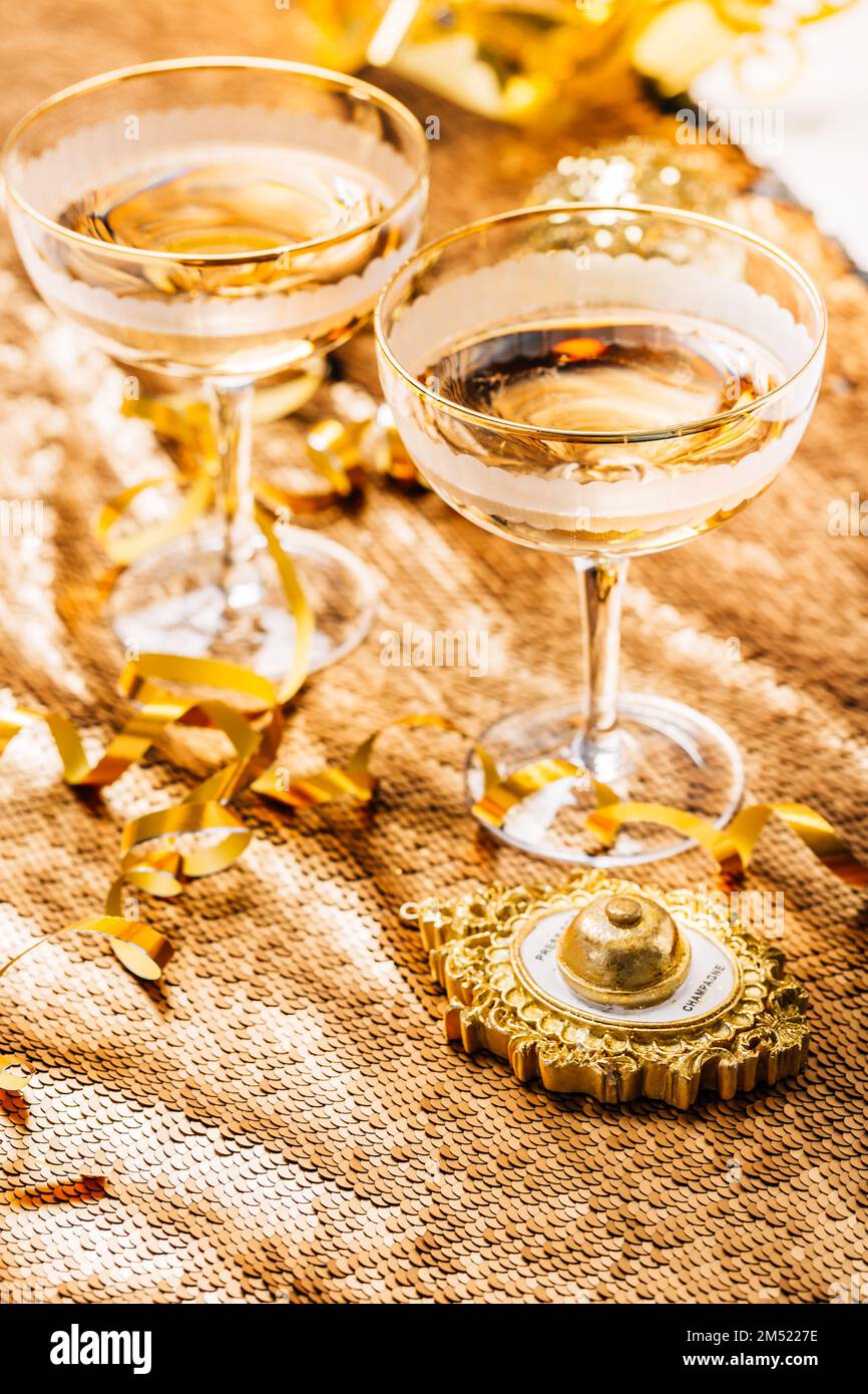 Deux verres de vin mousseux sur une table de fête pour le nouvel an, la fête ou le carnaval. Bouton-poussoir cloche pour champagne, dans un ton doré Banque D'Images