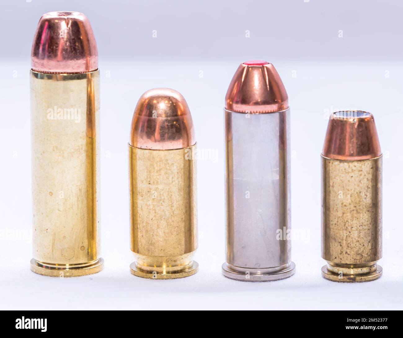 Quatre balles de calibre différent, un camoul de 454, 44 spécial, 45 acp et un calibre de 40 alignés sur un fond blanc Banque D'Images