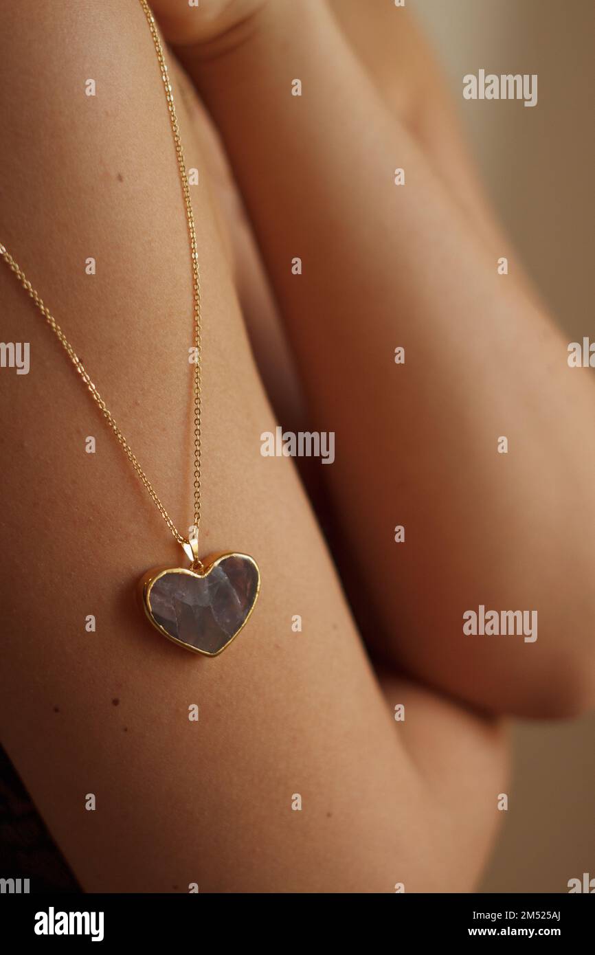 Amulette en forme de coeur doré sur l'épaule d'une fille Banque D'Images