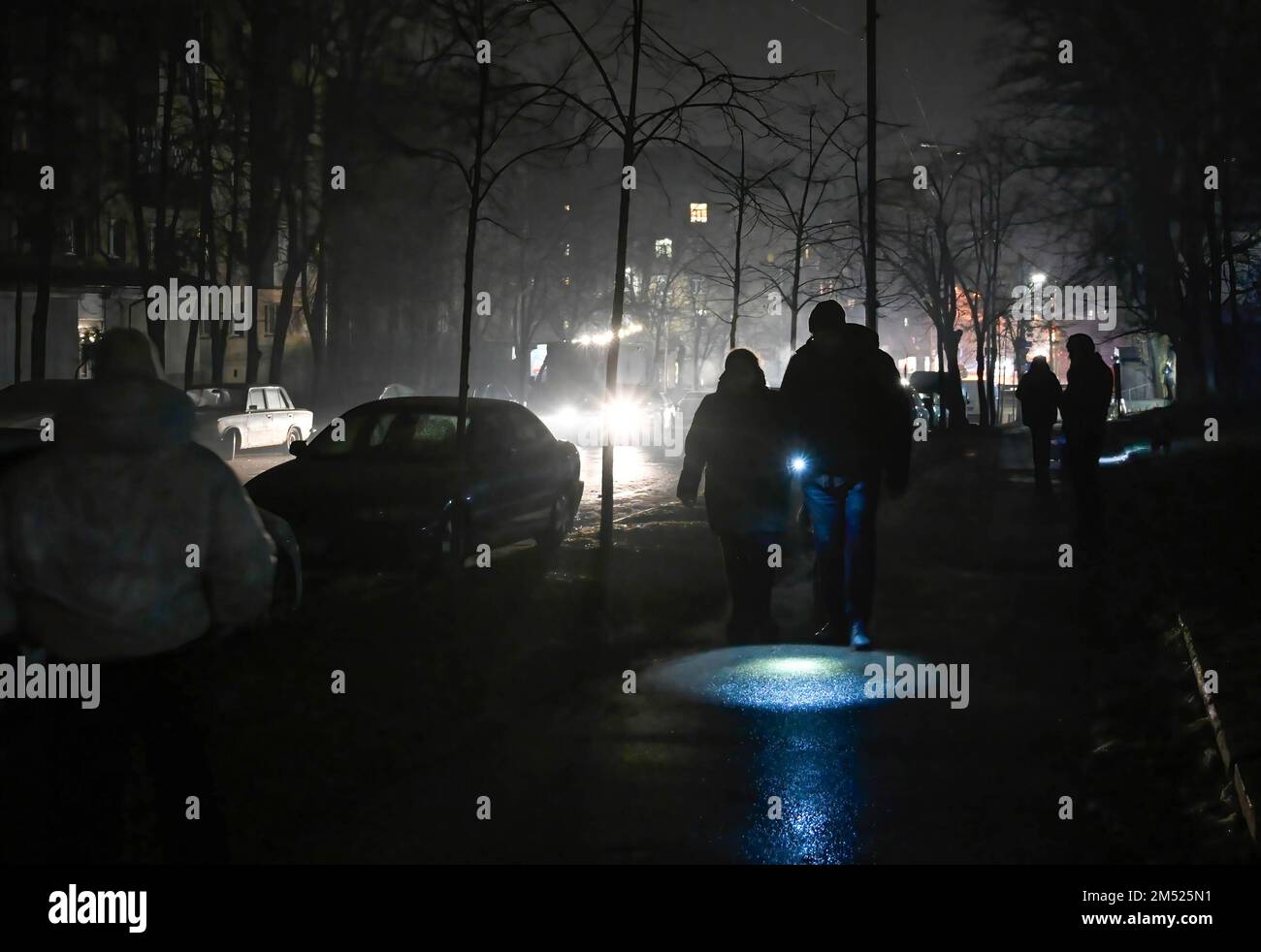 Les gens utilisent une lampe de poche lorsqu'ils marchent dans une rue sombre lors d'une panne de courant à Kiev. L'armée russe a mené des attaques massives de roquettes et de drones kamikaze sur les infrastructures énergétiques ukrainiennes. Après de graves dommages au réseau électrique dans de nombreuses villes d'Ukraine, la compagnie nationale d'électricité Ukrenergo a introduit des coupures d'électricité d'urgence et toutes les heures. Banque D'Images