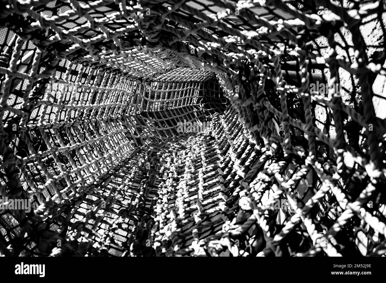 Vue sur un long tunnel en corde de lit en toile sur une aire de jeux pour enfants Banque D'Images