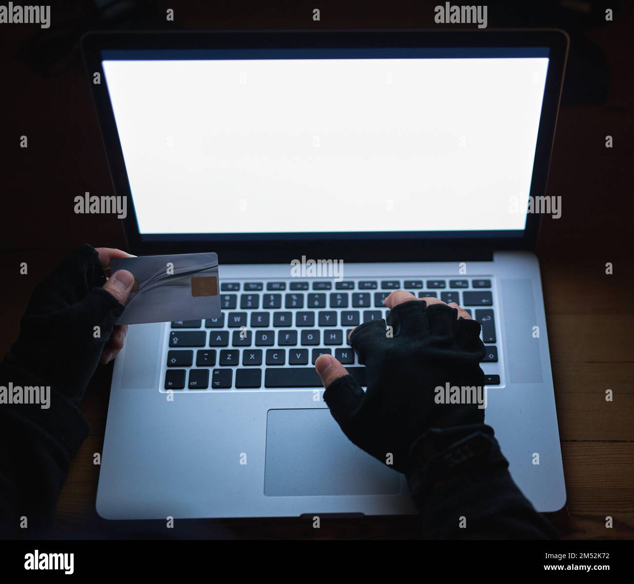 Vos informations sont toujours en danger. un pirate méconnaissable utilisant un ordinateur portable pour pirater un compte de crédit. Banque D'Images