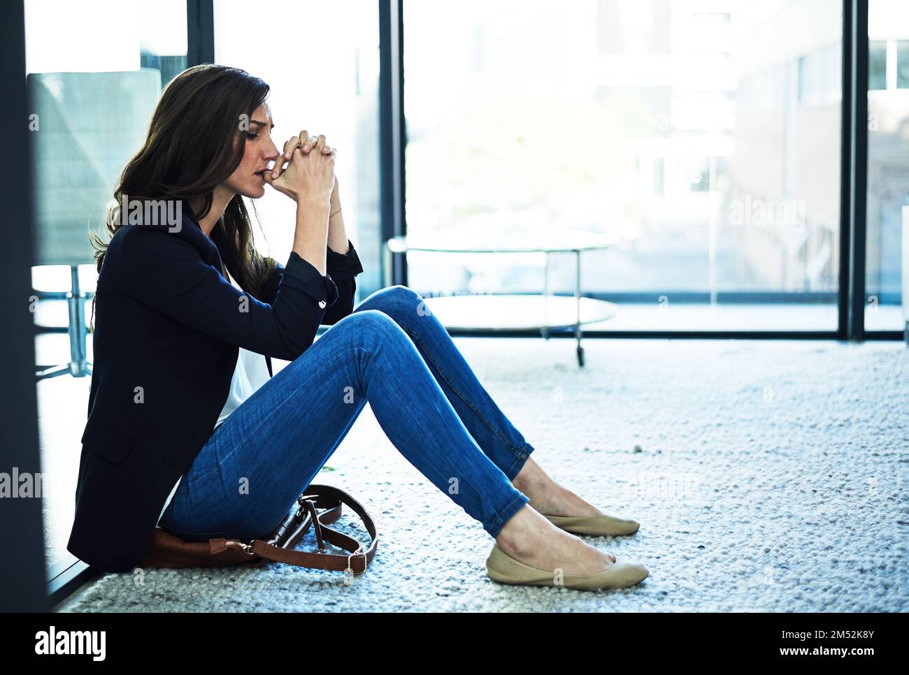 Fissure sous pression. une femme d'affaires stressée assise sur le sol à l'extérieur de la salle de réunion. Banque D'Images