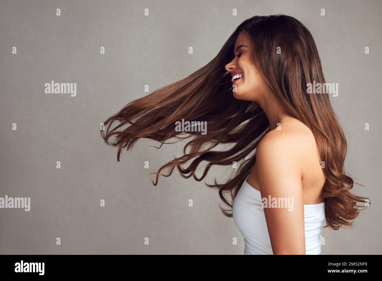 Qui pourrait dire non à avoir des cheveux magnifiques. Photo en studio d'une jeune femme belle avec de longs cheveux magnifiques posant sur un fond gris. Banque D'Images