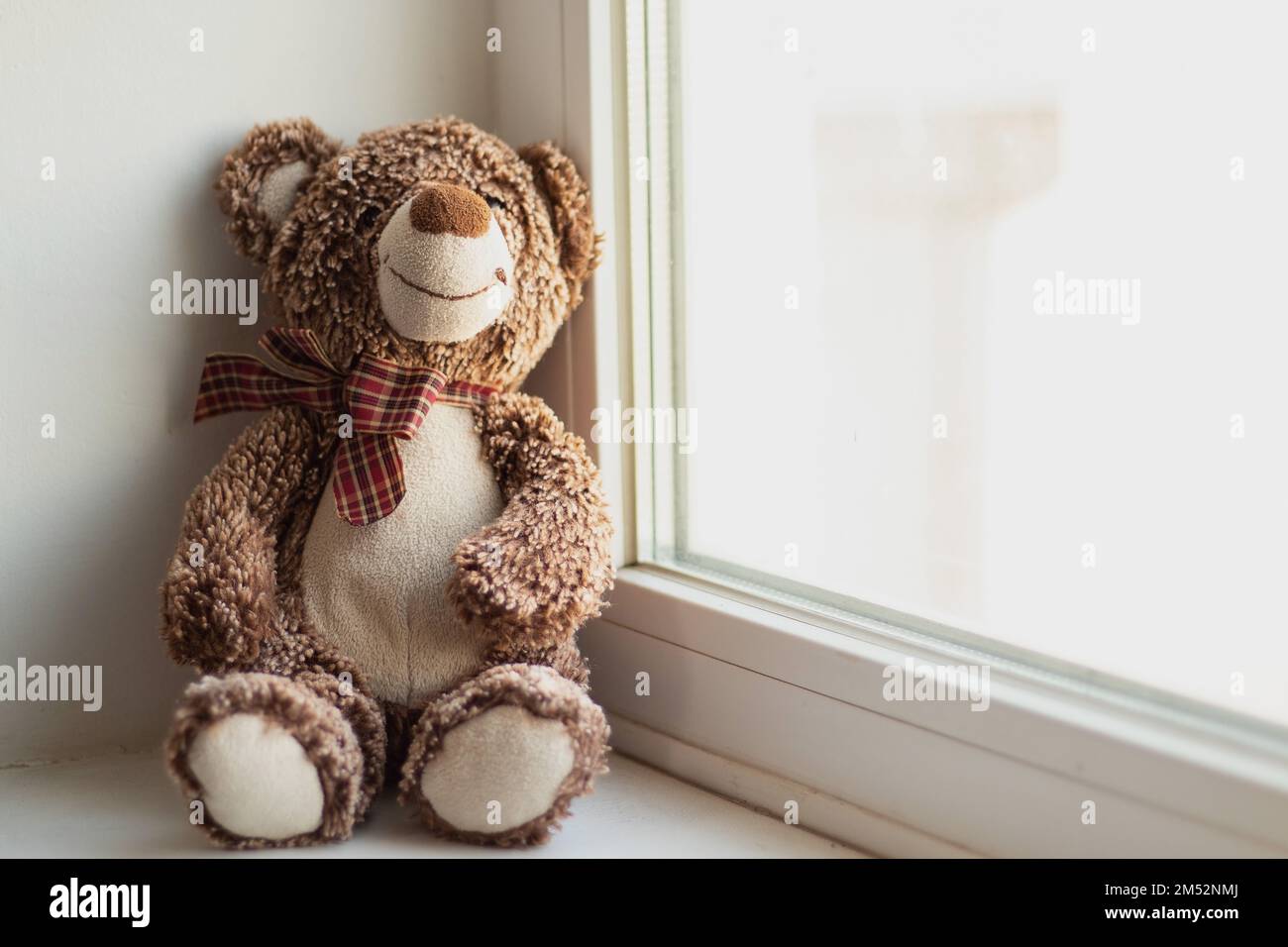 l'ours en peluche brun est assis sur la seule fenêtre, le jouet pour enfants Banque D'Images