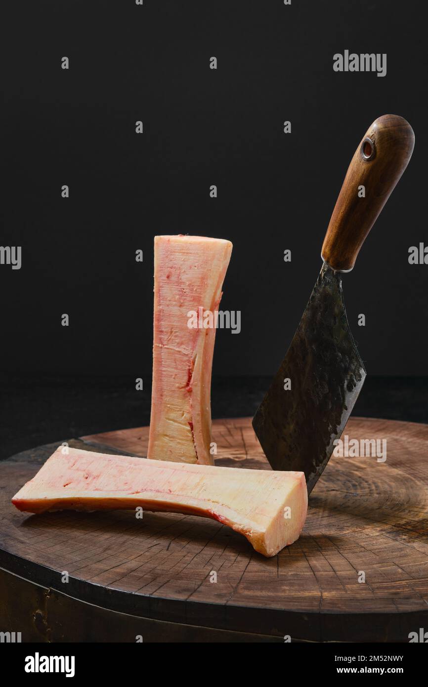 Grande moelle osseuse de bœuf hachée avec un cale sur la moitié sur une souche en bois Banque D'Images