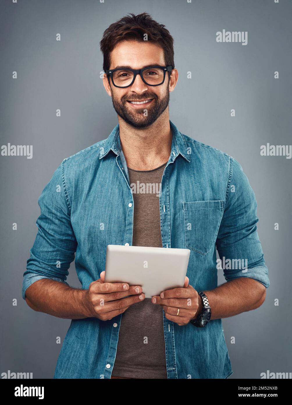 Je préfère garder les choses numériques. Photo en studio d'un beau jeune homme à l'aide d'une tablette numérique sur fond gris. Banque D'Images