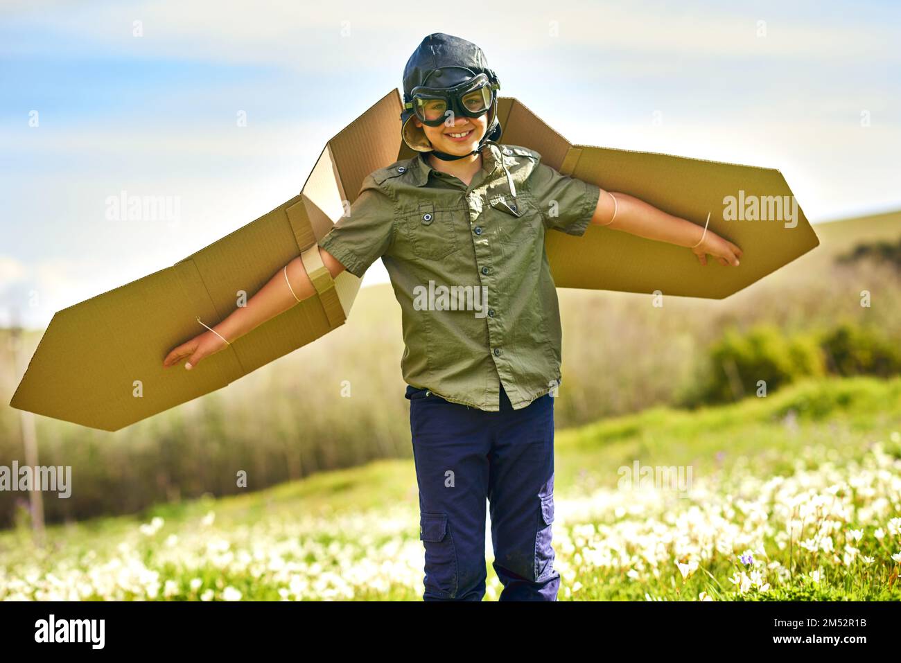 Décollage sur les compagnies aériennes imagination. un petit garçon ludiques prétendant être un avion avec une paire d'ailes en carton. Banque D'Images