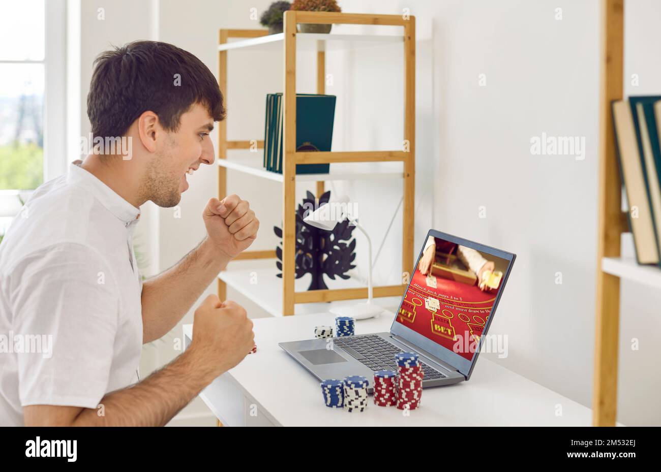 Excitée Guy est stupéfié à la grande victoire il a gagné en jouant au poker en ligne avec l'aide d'ordinateur portable. Banque D'Images