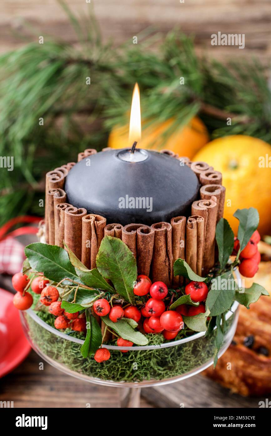 bougie décorée de bâtons de cannelle et de pommes rouges