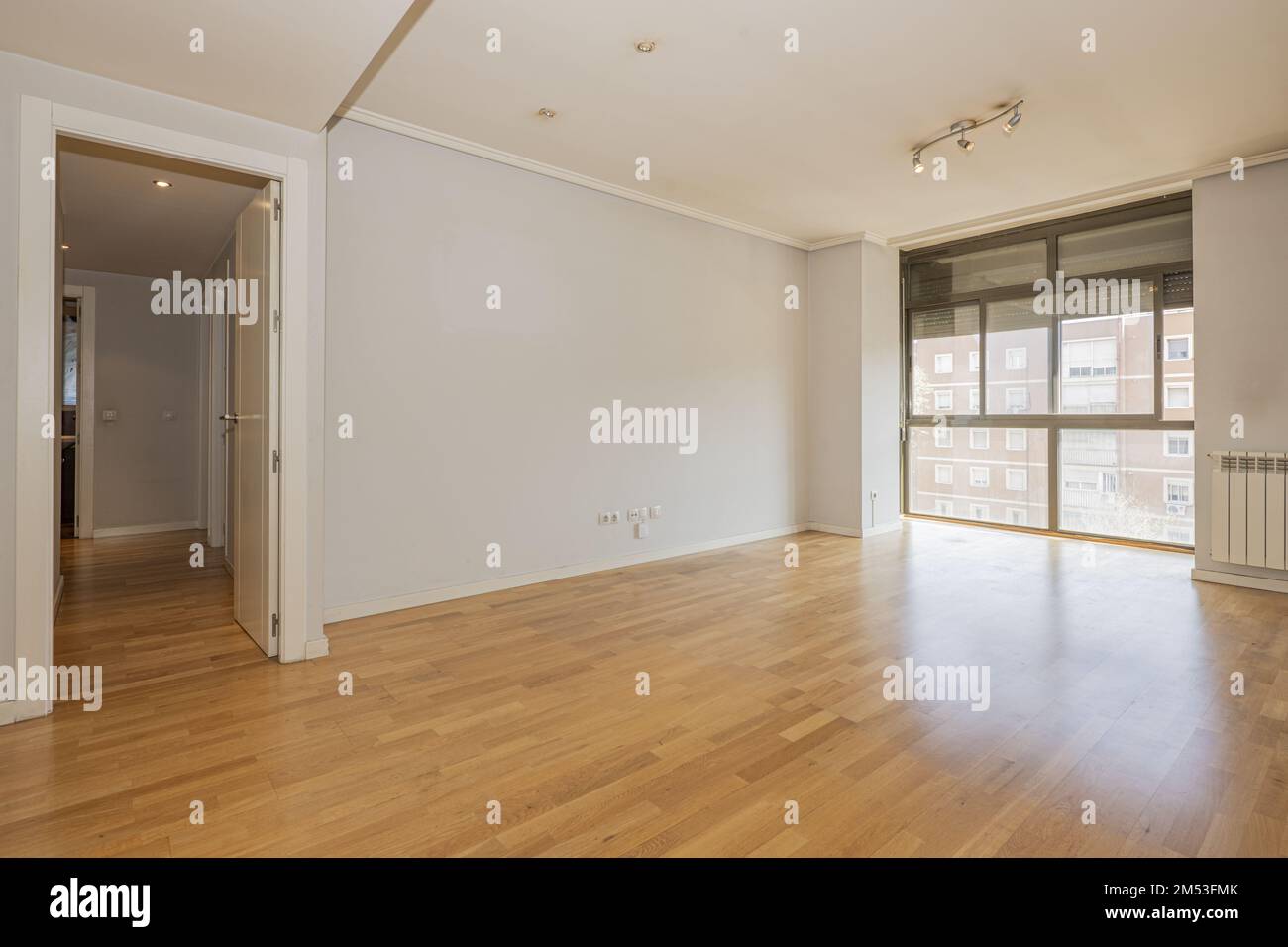 Chambre vide avec murs gris, portes intérieures en bois blanc lisse, baie vitrée avec aluminium noir et volets, moulures de plafond et bois de chêne f Banque D'Images