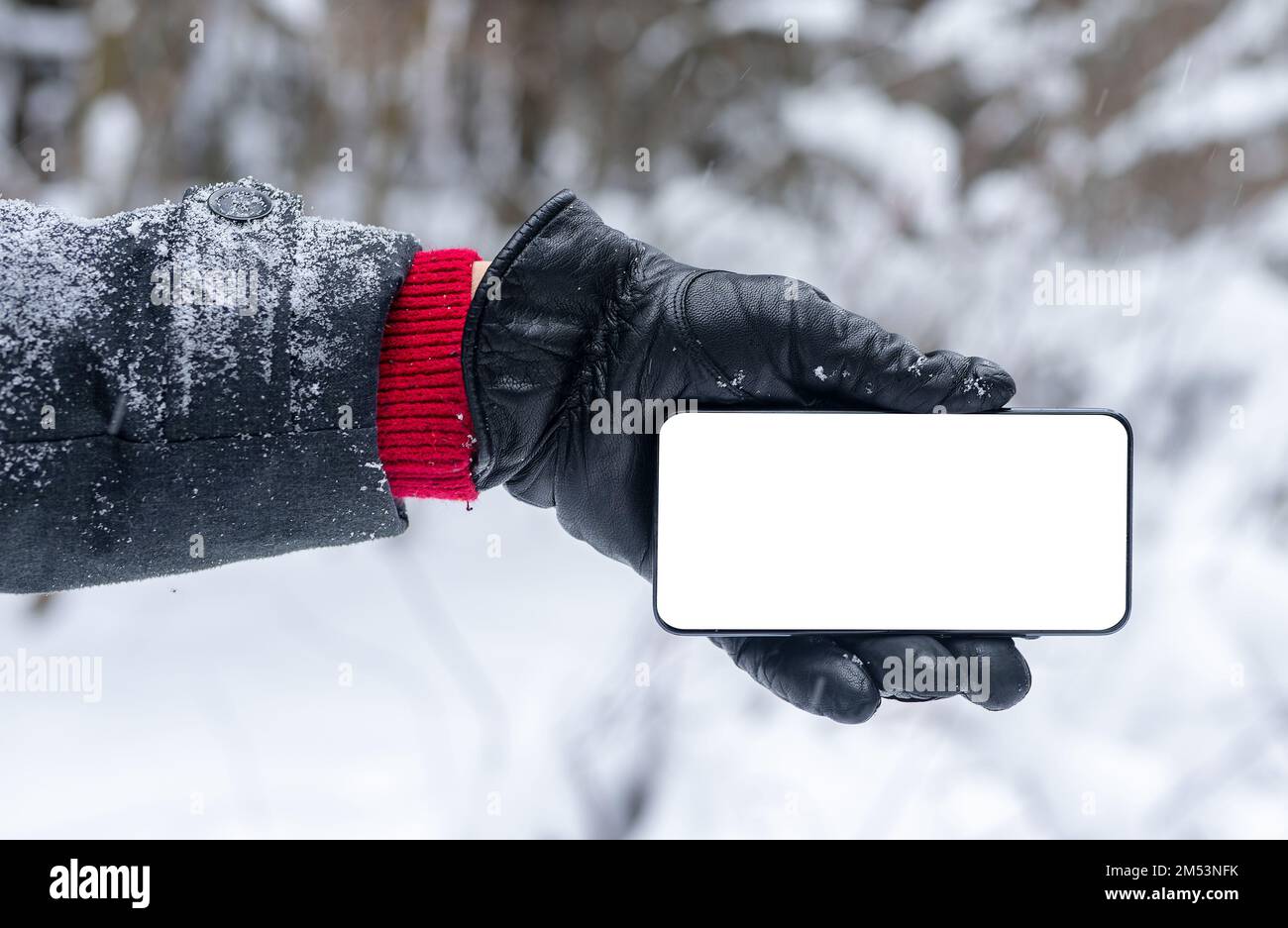 L'écran du téléphone portable se déforme dans les gants par temps hivernal avec de la neige. Photo de haute qualité Banque D'Images