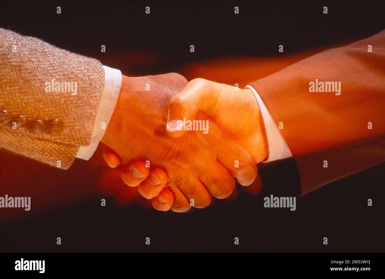 Gros plan de deux hommes d'affaires qui se secouent la main, image floue et chaleureuse Banque D'Images