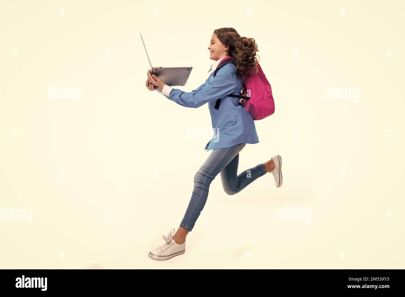 Retour à l'école. Adolescente tient un ordinateur portable. Les écoliers sur fond de studio blanc isolé. Courez et sautez, sautant un enfant. Banque D'Images