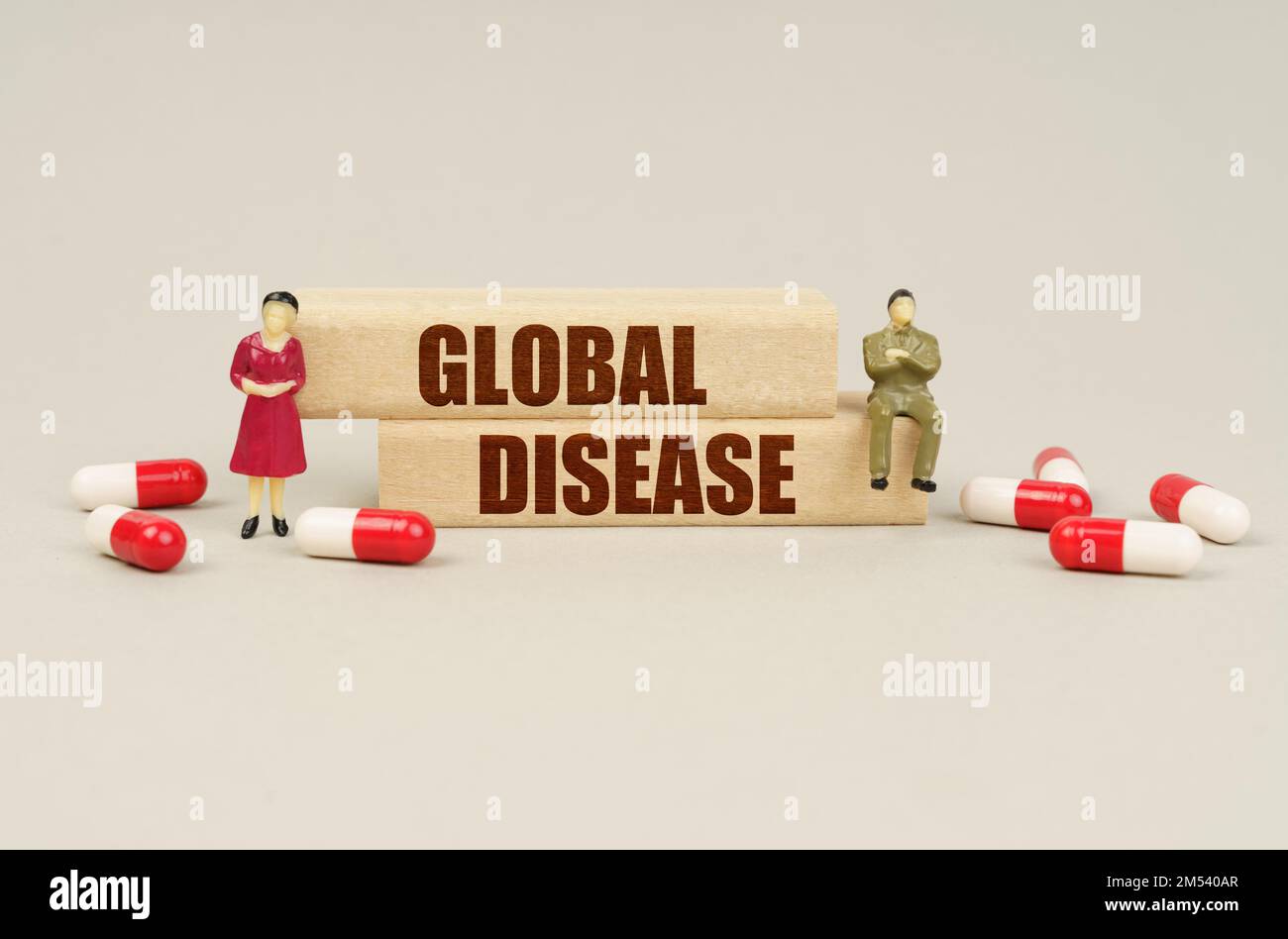 Concept médical. À côté des figurines miniatures des gens sont des comprimés et des blocs de bois avec l'inscription - MALADIE GLOBALE Banque D'Images