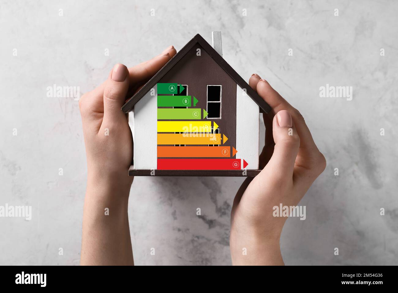 Mains de femme avec modèle de maison sur fond clair. Concept d'efficacité énergétique Banque D'Images