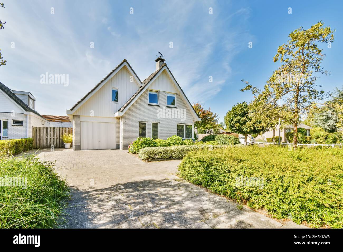 une maison avec des panneaux latéraux blancs et un ciel bleu en arrière-plan il y a une allée menant à la porte d'entrée Banque D'Images