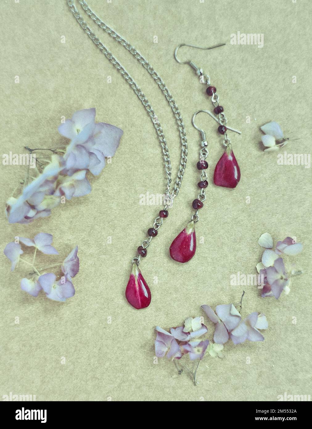 Ensemble de bijoux artisanaux à gros plan avec pétales rouges et fleurs fraîches concept photo Banque D'Images