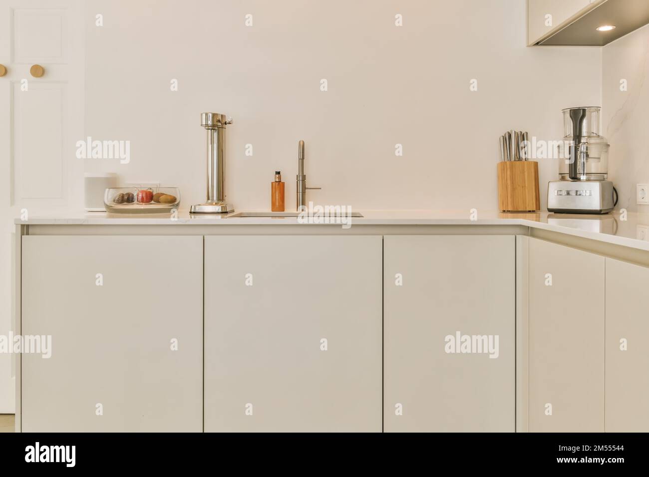 une cuisine avec des placards blancs et des appareils sur le comptoir en face de l'évier est une porte ouverte Banque D'Images