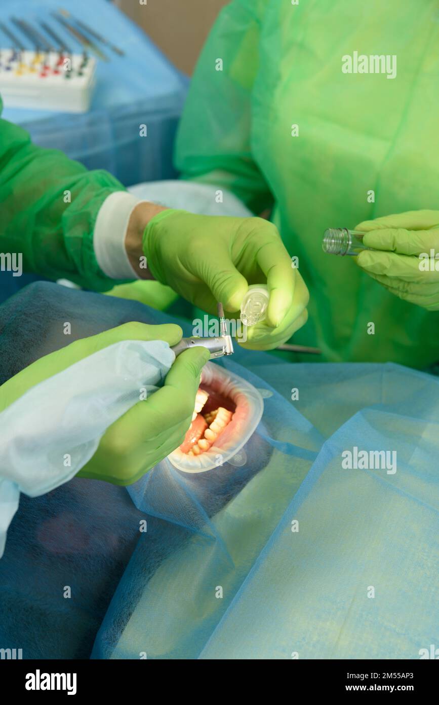 Gros plan de médecins attentifs effectuant des opérations chirurgicales en installant des implants dentaires dans la bouche du patient dans une clinique dentaire moderne. Banque D'Images